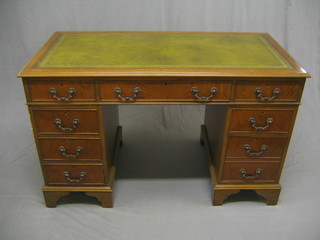 A Georgian style walnut kneehole pedestal desk with green inset tooled leather writing surface above 9 long drawers 47"