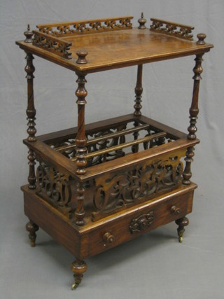 A Victorian figured walnut Canterbury, the raised top with pierced three-quarter gallery, raised on turned supports, the base fitted a 3 division Canterbury with pierced panels to the side, the base fitted a drawer (some old worm to right hand column and finials to the front reduced in height) 24"