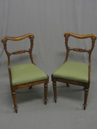 A pair of William IV mahogany spoon back dining chairs with carved mid rails and upholstered drop in seats, raised on turned and reeded supports