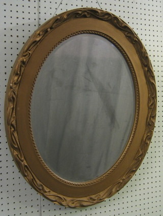 An oval bevelled plate wall mirror contained in a decorative gilt frame 25"