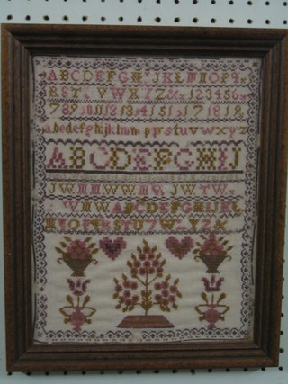 A 20th Century wool work sampler with alphabet and decorated a tree 11" x 9" contained in an oak frame