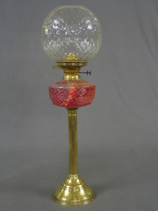 A Victorian pink tinted glass oil lamp reservoir with white shade, raised on a brass reeded column