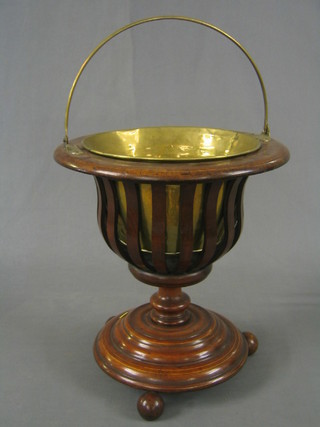 A 19th/20th Century turned mahogany planter with brass liner, raised on a circular base with 3 bun feet, 15"