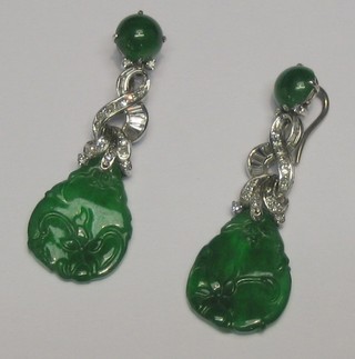A pair of carved jade coloured pendant drop earrings surmounted by baguette and other cut diamonds