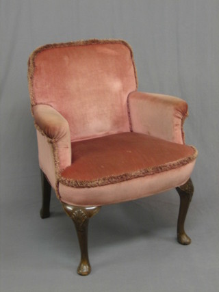 A 1950's Queen Anne style walnut framed armchair upholstered in pink Dralon, raised on cabriole supports