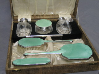 An Art Deco silver and green enamelled 7 piece dressing table set comprising clothes brush, hand mirror, hair brush, comb, perfume atomiser, perfume bottle and circular dressing table jar and cover, cased