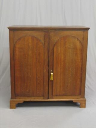 A Victorian oak cupboard enclosed by arch shaped panelled doors, raised on bracket feet 43".