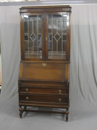 An Art Nouveau oak students bureau bookcase, the upper section with moulded cornice, the shelved interior enclosed by lead glazed panelled doors, the base with fall front revealing a well fitted interior above 2 long drawers raised on turned and bulbous supports 36"