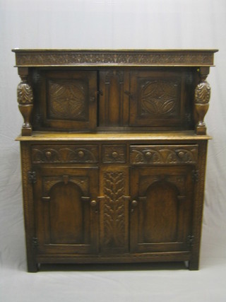 A carved oak Jacobean style court cupboard, the upper section fitted a double cupboard enclosed by doors, the base fitted 1 long and 2 short drawers above double cupboard 50"