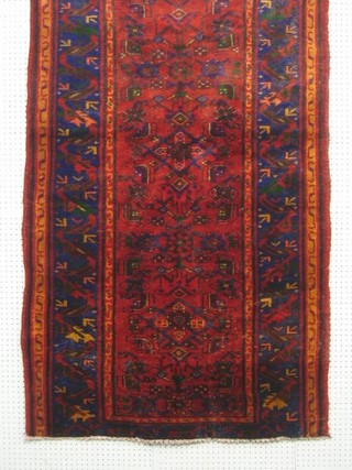 A contemporary Persian red and blue ground rug with geometric design to the centre within multi-row borders 82" x 43"