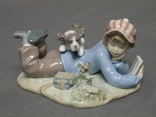 A Lladro figure of a boy reclining and reading a book with dog and bird, based E17E, 6",