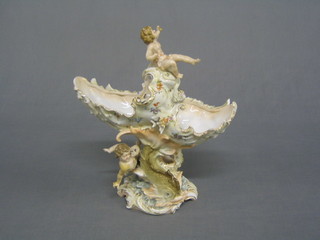 A porcelain table centre piece in the form of a shell supported by cherubs 9"