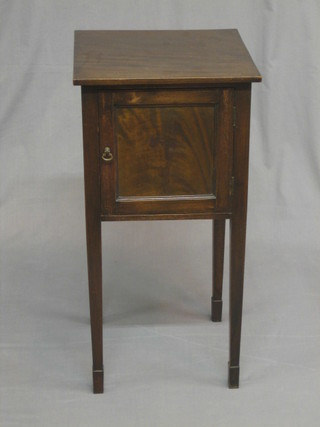 An Edwardian mahogany bedside cabinet enclosed by a panelled door, raised on square tapering supports ending in spade feet 14"