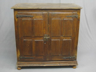 An 18th/19th Century Continental pine cupboard enclosed by panelled doors with iron hinges, raised on bun feet 41"