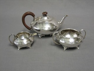 An Art Nouveau planished metal 3 piece tea service with circular teapot, twin handled sugar bowl and cream jug