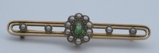 An Edwardian 15ct gold bar brooch set an oval peridot and pearls