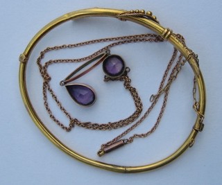 A gilt metal brooch and a gold chain hung an amethyst pendant