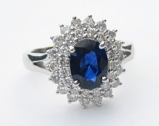A handsome 18ct white gold dress ring set a large oval cut sapphire surrounded by 2 rows of brilliant cut diamonds