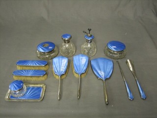 A 12 piece Art Deco silver and blue enamelled backed dressing table set comprising rectangular pin tray 5", circular cut glass powder bowl and cover 4", silver button hook, shoe horn, hand mirror, 2 hair brushes (1 with damage to enamel), circular cut glass hair tidy 4", circular cut glass jar and cover 2" (damage to enamel), pair of hair brushes, circular scent bottle, perfume  atomiser, Birmingham 1930-31