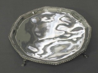 A circular silver plated salver with bracketed border, raised on 3 hoof feet 8"