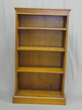 A 19th Century style yew pedestal bookcase with moulded and dentil cornice, the interior fitted adjustable shelves, raised on a platform base 22"