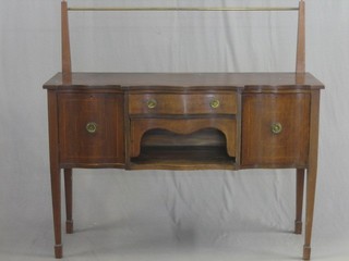 An Edwardian inlaid mahogany Georgian style sideboard of serpentine outline, the back with brass rail, fitted 1 long drawer above a recess, flanked by a pair of cupboards, raised on square tapering supports ending in spade feet 54"