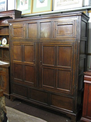 An 18th/19th Century oak cupboard of panelled construction, enclosed by 4 panelled doors, raised on bracket feet, 66"