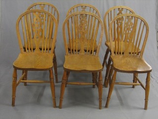 A 20th Century set of 6 elm Windsor stick and wheel back dining chairs with solid seats, raised on turned supports