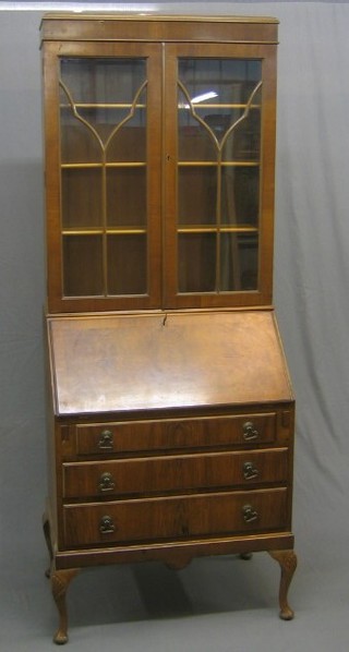 A 20th Century Georgian style walnut bureau bookcase, the upper section fitted adjustable shelves enclosed by glazed doors, the base with fall front revealing a well fitted interior above 3 long drawers, raised on cabriole supports 31"