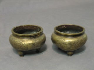 A pair of 19th Century circular Oriental bronze jars with engraved decoration, raised on 3 feet, the bases with seal mark, 3 1/2"