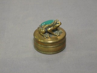 A 19th Century circular gilt metal trinket box, the finial in the form of a seated toad set a green hardstone cabouchon cut stone, 2"