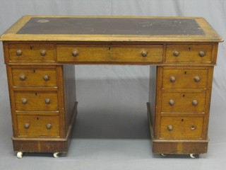 A Victorian honey oak kneehole pedestal desk with brown inset writing surface above 9 drawers, 49"