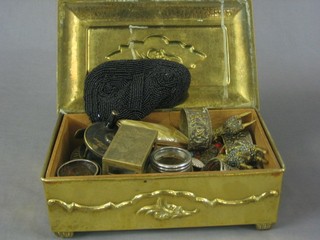 An embossed metal box containing a collection of metalware