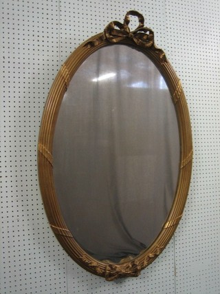 An oval plate mirror contained in a gilt plaster frame surmounted by a bow, 43"