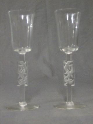 A pair of Lalique champagne flutes, the rectangular stems with cut intaglio birds in flight, signed R Lalique (chip to rim and stem, 1 in good order)