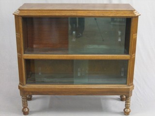 A 19th/20th Century Globe Wernicke style 2 tier bookcase enclosed by glazed panelled sliding doors, raised on turned and bun feet 43"