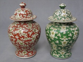 A pair of Oriental style floral patterned lidded urns and covers of baluster form 12"