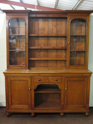 A  19th Century honey oak dresser, the raised back with moulded cornice, fitted 3 shelves flanked by a pair of cupboards enclosed by arched panelled doors, the base fitted a drawer above a recess flanked by a pair of cupboards, raised on turned supports 68"