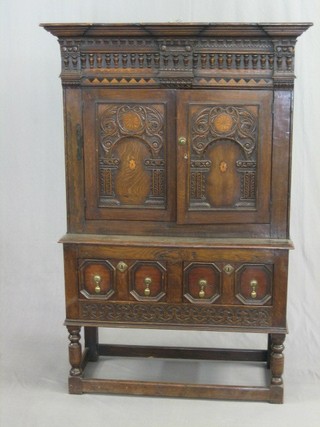 An 18th/19th Century Continental carved oak cabinet on chest, the upper section with moulded and dentil cornice, the interior fitted adjustable shelves enclosed by arched carved panelled doors, the base fitted 2 drawers, raised on turned and block supports 40"
