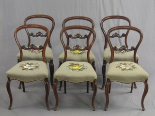 A set of 6 Victorian rosewood balloon back dining chairs with carved mid-rails and upholstered seats, raised on French cabriole supports