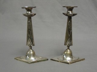 A pair of German Art Nouveau embossed silver candlesticks with mask decoration, raised on square feet, marked Bruglocher 19 ozs