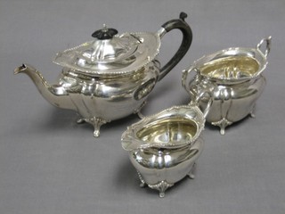 A silver oval 3 piece tea service with ribbon border comprising teapot (some dents) cream jug, twin handled sugar bowl, all raised on panel supports, Sheffield 1916, 21 ozs