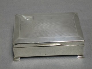A silver cigarette box with engine turned decoration, raised on ogee bracket feet, Birmingham 1934, 5" (marks rubbed)