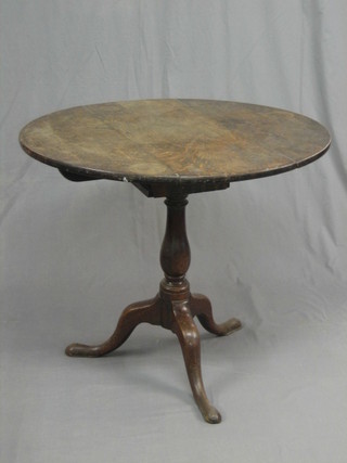 An 18th Century oak circular tea table with bird cage action, raised on a turned column with tripod supports 33"