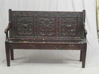 A Victorian carved oak settle with high back, raised on square tapering supports 54"
