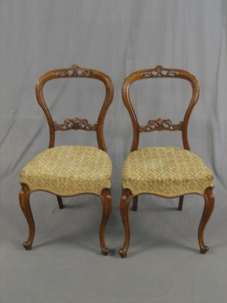 A pair of Victorian pierced walnut balloon back dining chairs  of serpentine outline with shaped mid rails, raised on French cabriole supports