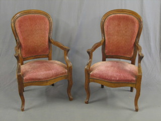A pair of 19th Century French walnut open arm salon chairs, raised on cabriole supports upholstered in rose pink velvet (1 with old Blacksmith's repair to back)