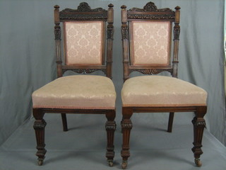 A set of 4 Edwardian carved walnut dining chairs with upholstered seats and backs, raised on turned fluted columns