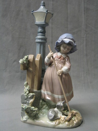 A Lladro figure of a standing bonnetted girl with cat, by a lamp post and fence, the base marked FSN 5286, 13"