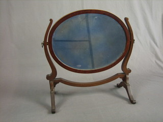 An oval bevelled plate dressing table mirror contained in an inlaid  mahogany frame